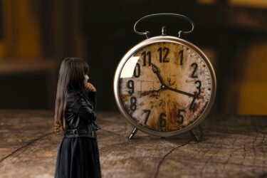 A woman stands pondering an oversize clock. The image symbolizes brainstorming cures for procrastination.
