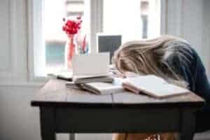 woman leaning on table, looking overworked, exhausted, and like she can never relax