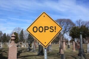 A street sign in front of a graveyard reads "OOPS!" symbolizing the blog topic of my graduate school regrets.