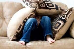 little boy on a couch hiding under the cushions.