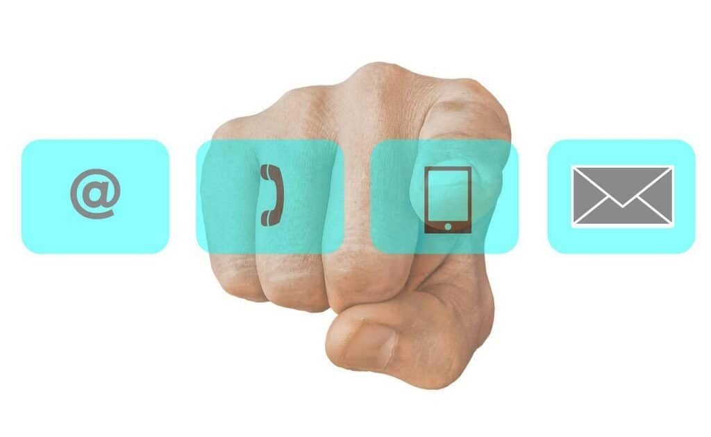 Image of a hand pointing towards contact icons, like a phone, email, computer, and social media indicator. Featured image for how to contact potential PhD advisors.
