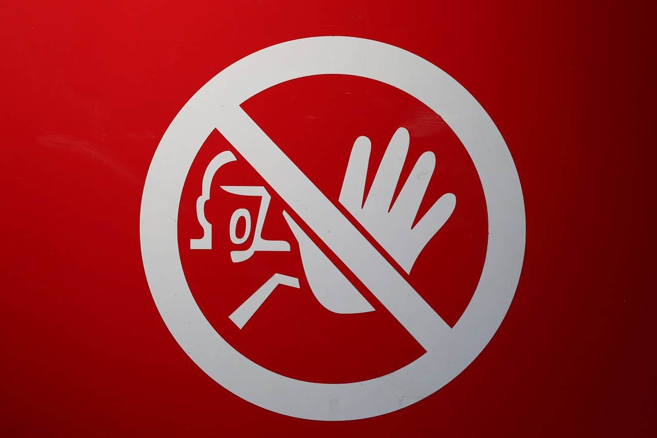 Image of a warning sign with a person's outstretched hand held up, palm facing out in a blocking posture.
