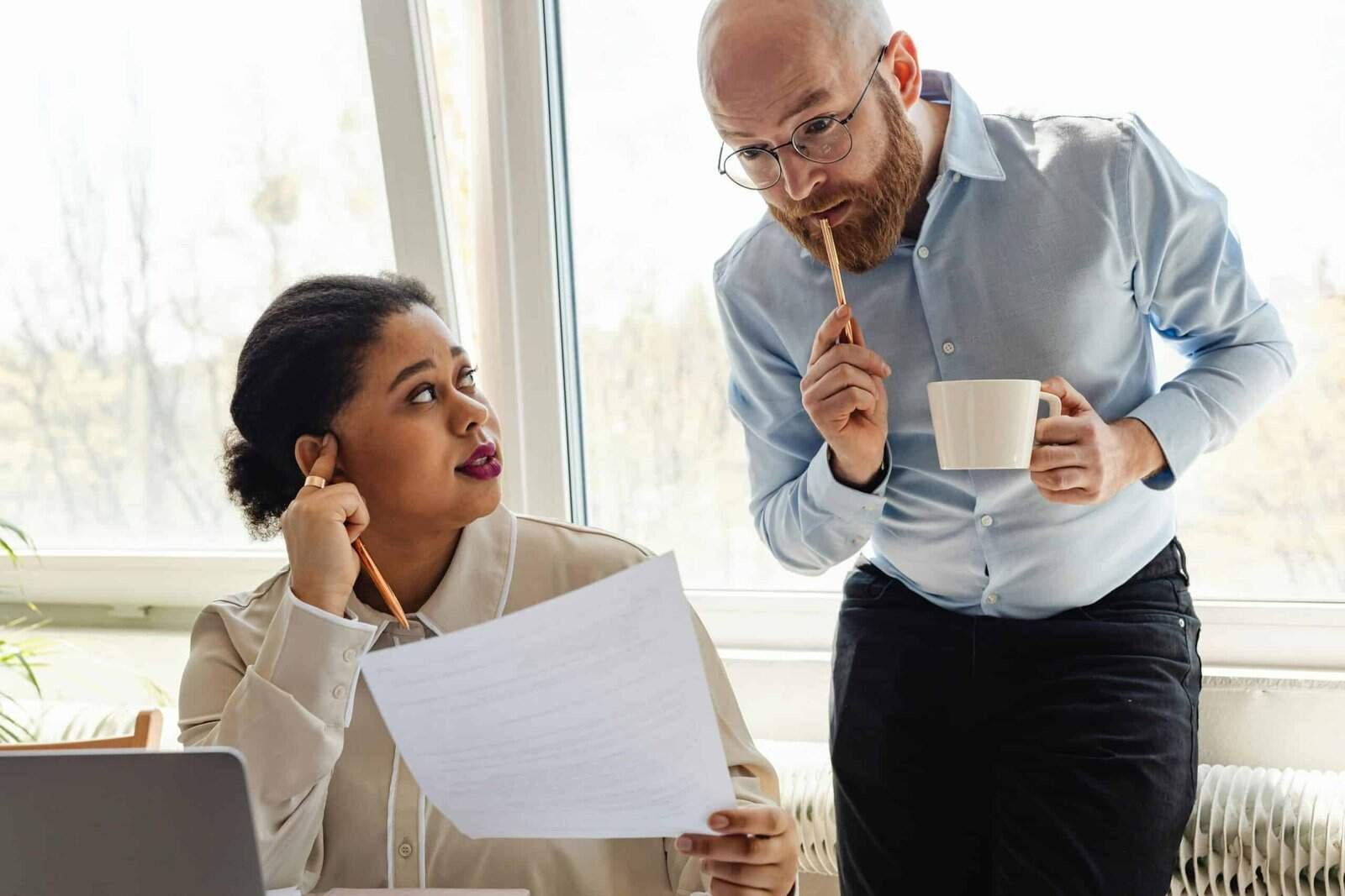 Image of research advisor looking at a piece of paper held up by a graduate student sitting next to them.