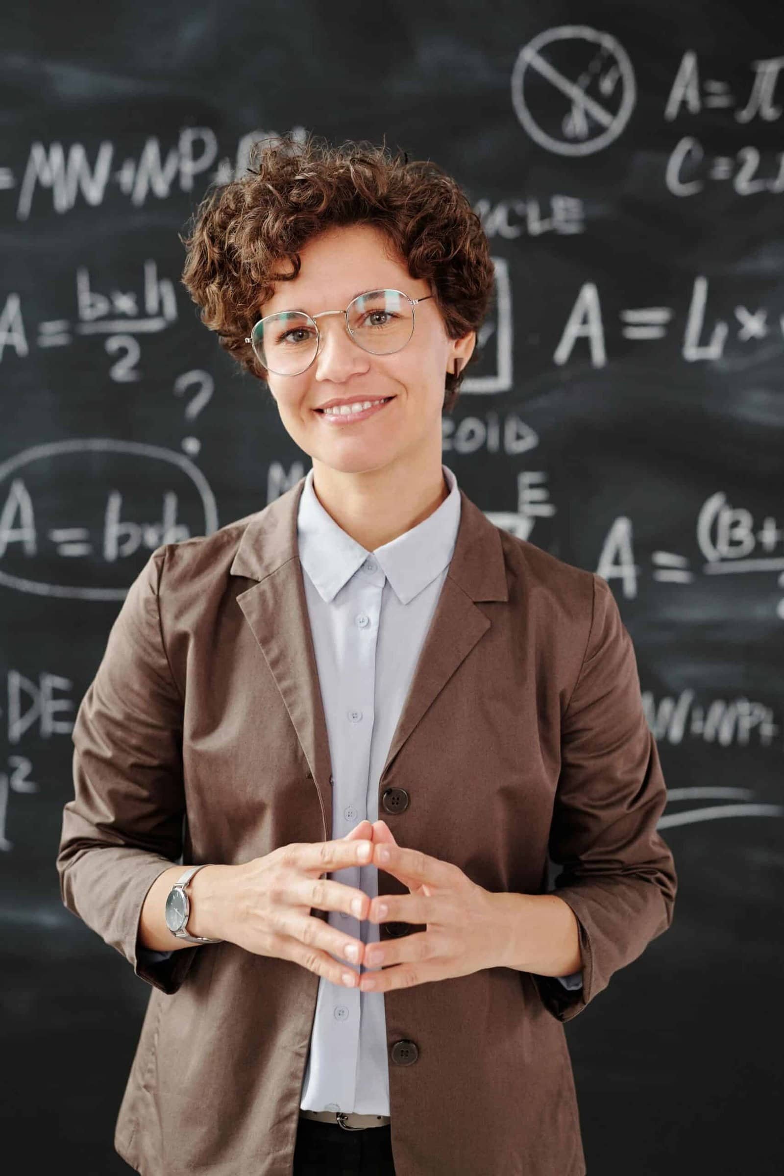 Image of a dissertation advisor standing in front of a blackboard, which has mathematical formulas on it.